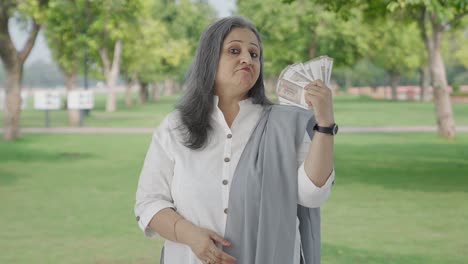 Confident-Indian-mother-using-money-as-fan-in-park