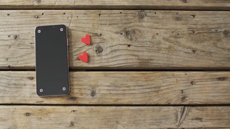 corazones de madera y teléfono inteligente en fondo de madera en el día de san valentín