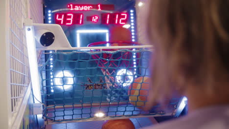 teenage boy playing arcade basketball