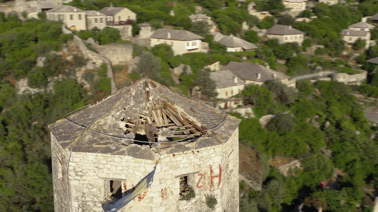 All-round view of castle tower with broken roof at base of mountain with view of a village