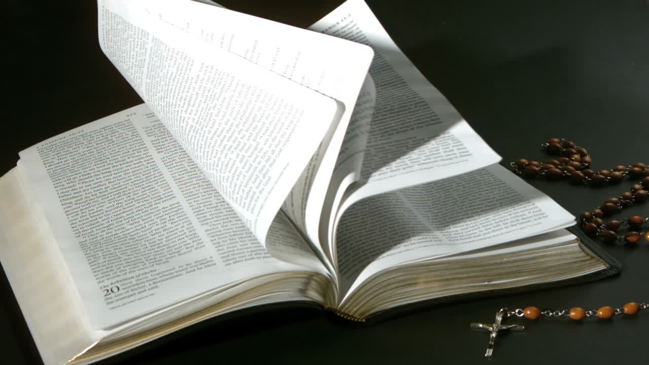 Pages de la Bible tournant au vent à côté d'un chapelet