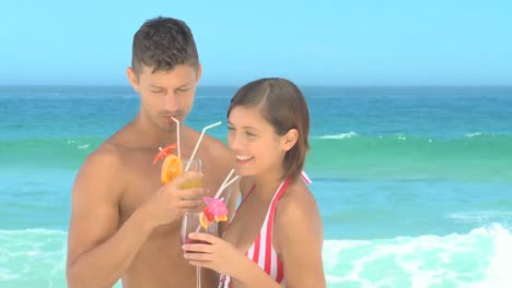 pareja linda bebiendo cócteles en una playa