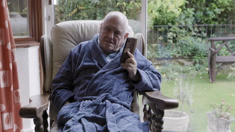 elderly man in robe using phone