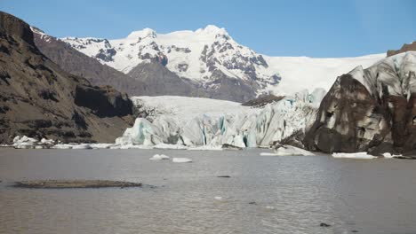 laguna glaciar con hielo flotante y montañas cubiertas de nieve bajo un cielo azul claro en islandia