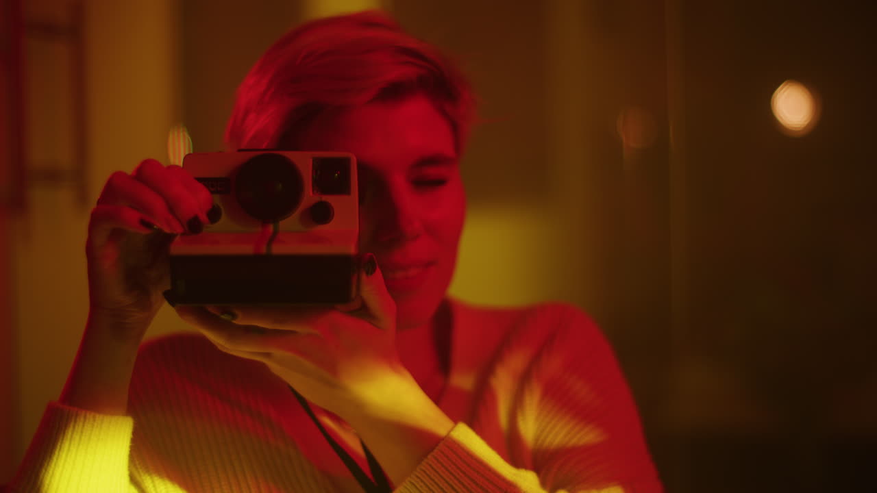 Woman Taking a Polaroid Photo in a Neon-Lit Room