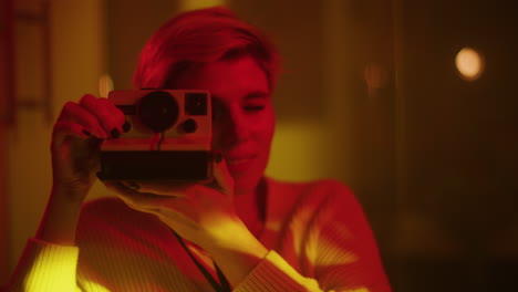 woman taking a polaroid photo in a neon-lit room