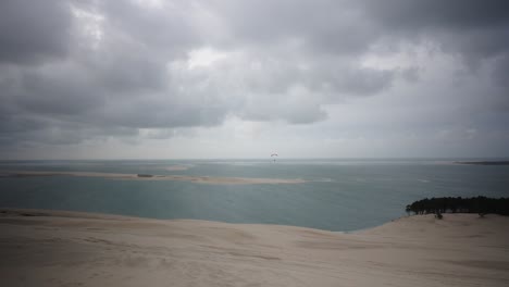 Biggest-sand-dune-du-pilat-in-France,-one-person-paragliding,-bad-weather-wide-angle-view