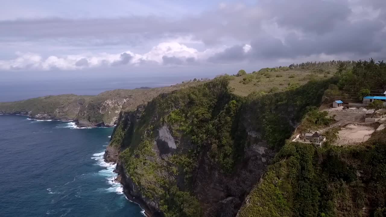 Smooth aerial view flight panorama curve flight drone shot dramatic clouds Kelingking Beach at Nusa Penida in Bali Indonesia is like Jurassic Park Cinematic nature cliff view above by Philipp Marnitz