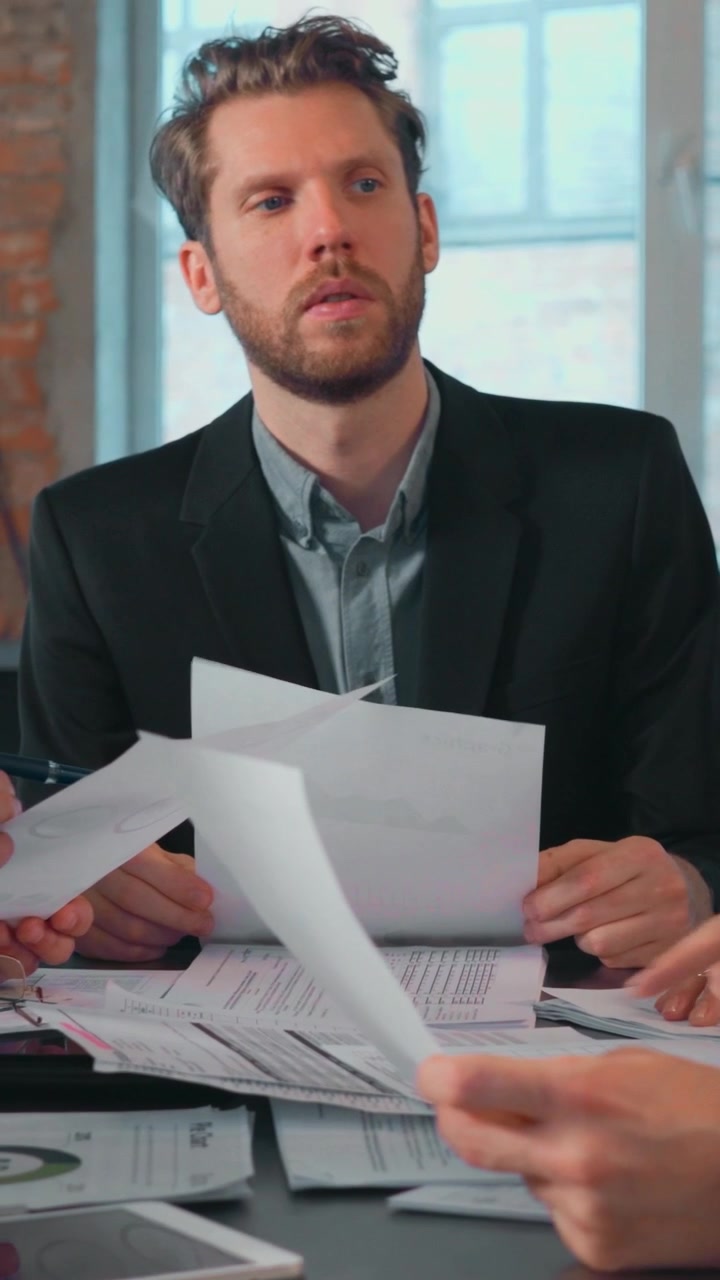 Un uomo d'affari esamina documenti a una riunione in un ufficio moderno.