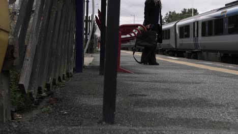 business woman waiting to board train on platform with briefcase wide shot