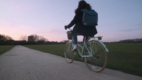 Hinteres-Profil,-Folgeaufnahme-Einer-Jungen-Frau,-Die-Bei-Sonnenuntergang-Auf-Einem-Schotterweg-Radelt