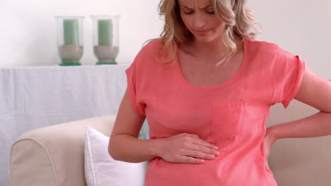 pregnant woman with backache touching back and belly