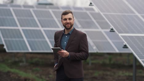 Retrato-De-Un-Joven-Con-Un-Fajo-De-Dinero-Y-Una-Tableta-En-El-Fondo-De-Una-Planta-De-Energía-Solar