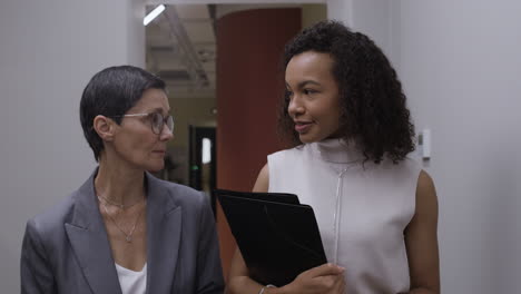 businesswomen in conversation in office corridor