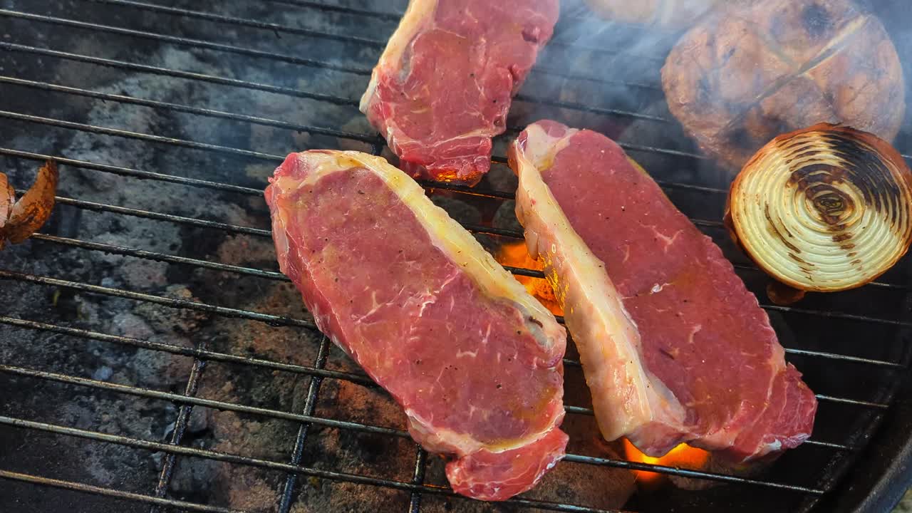 Flame grilled steaks and mushrooms over the hot coals with bursts of fire and smoke.