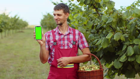 Hombre-Caucásico-Agricultor-Mostrando-La-Tecla-De-Croma-De-Pantalla-Verde-Apuntando-Al-Teléfono-Inteligente-Buena-Cosecha-Avellanas