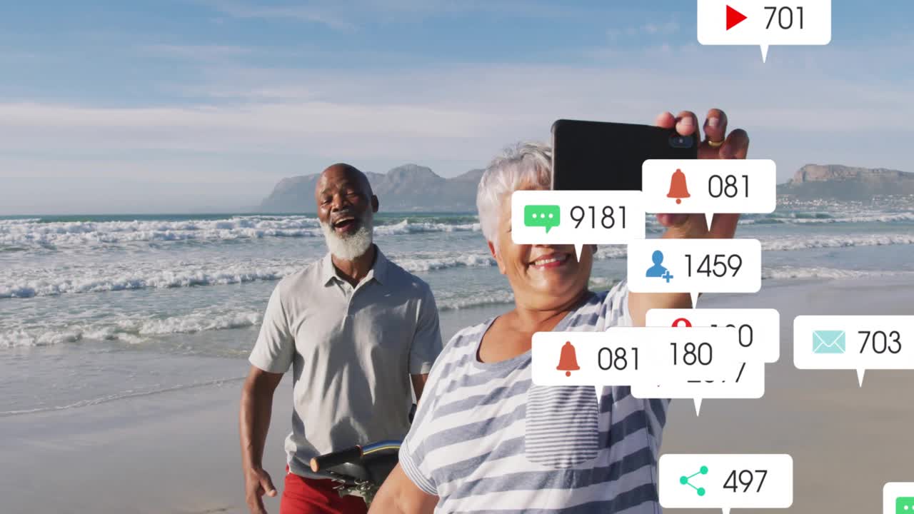 Woman raising smartphone for beach selfie with partner by bike and social media icons multiplying