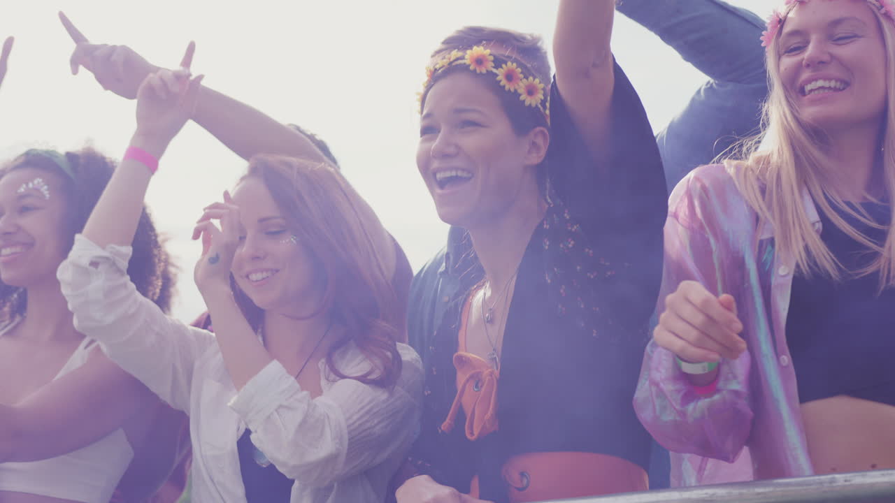 grupo de jóvenes amigos bailando detrás de una barrera en un festival de música al aire libre