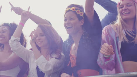 group of young friends dancing behind barrier at outdoor music festival