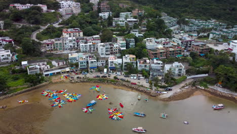 ariel drone orbit shot over sai kung hong kong beach village house. revealing water activity in private beach and boar trip yacht in hd 4k