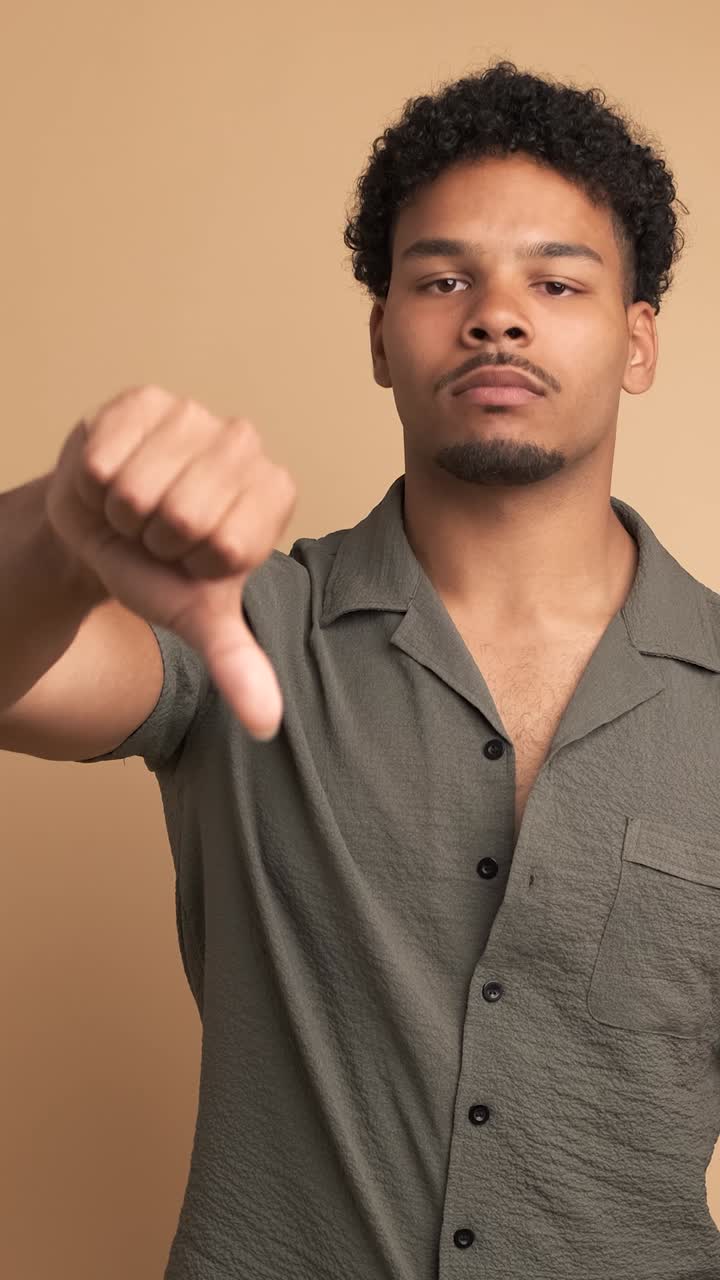 Sad man making thumbs down sign and shaking head in displeasure