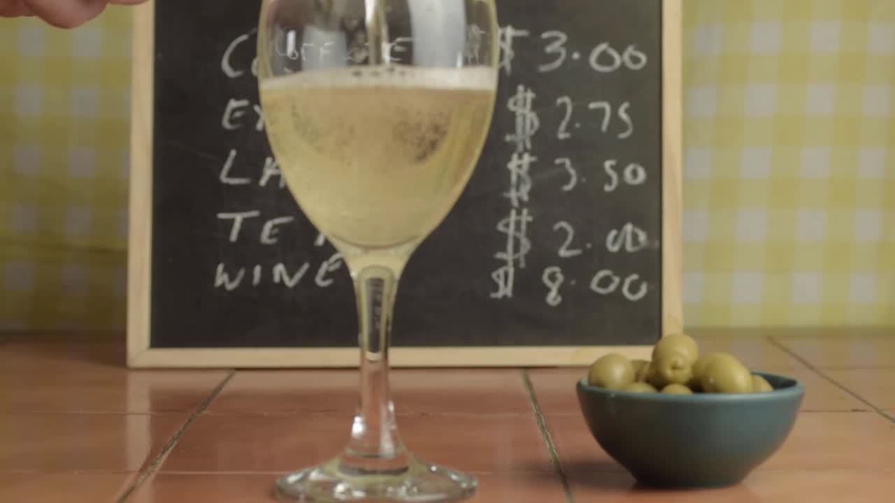 Hælder hvidvin op i glas på en café