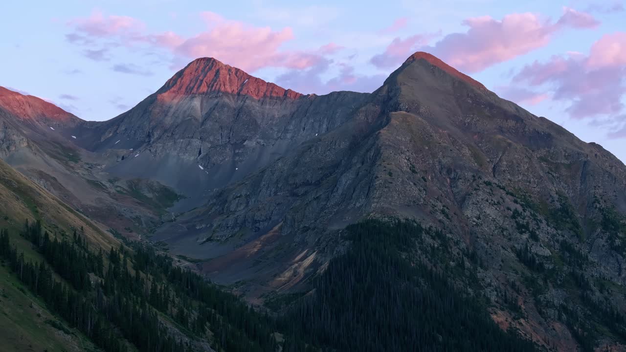 Latar belakang telefoto drone dengan puncak gunung bergerigi yang bersinar oleh alpenglow di atas American Basin