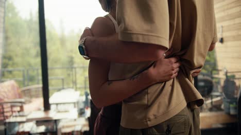 Close-up-shot:-a-guy-and-a-girl-hugging-in-an-industrial-country-house-overlooking-a-green-coniferous-forest