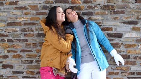 Cute-twins-in-winter-coats-leaning-on-wall