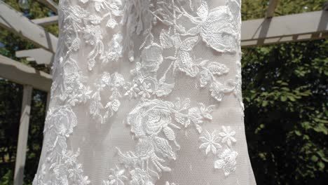 beautiful up close reveal of the material design of a fashion wedding dress outside during the summer at strathmere wedding and event center in ottawa, canada