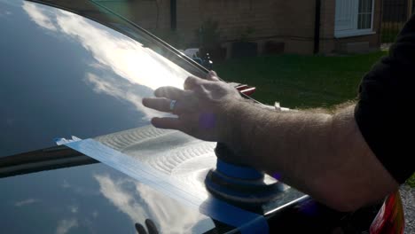 polishing a black car trunk boot with a small machine polisher