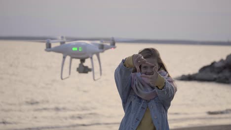 funny girl making video on the beach using drone