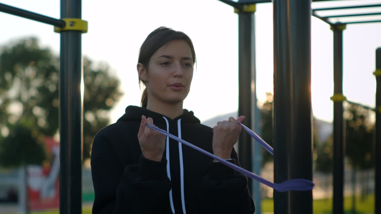 mujer trabajando con banda de resistencia en un gimnasio al aire libre