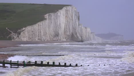 the sea breaks along wooden jetties along the shore of the white cliffs of dover at beachy head england 1