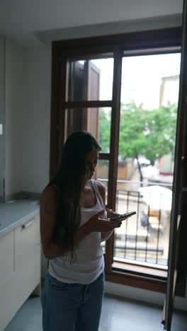 mujer usando el teléfono en una cocina