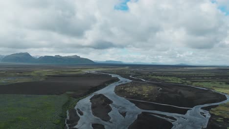 ascending above an extensive flowing river and panoramic wetland in south coast of iceland