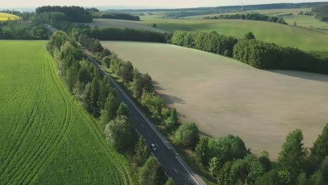 üppige,-Frühlingshafte,-Abwechslungsreiche-Landschaft-Mit-Einer-Straße,-Auf-Der-Autos-Vorbeifahren