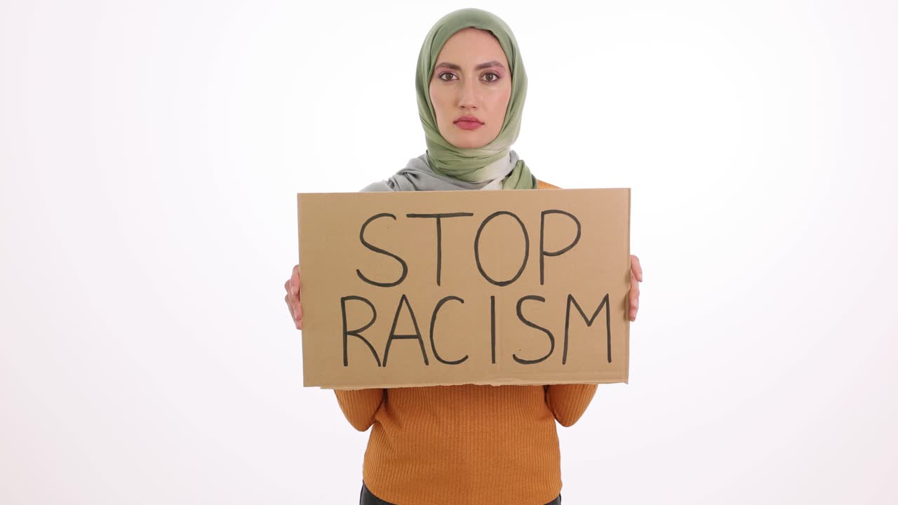 Donna con hijab che tiene un cartello 'STOP AL RAZZISMO'
