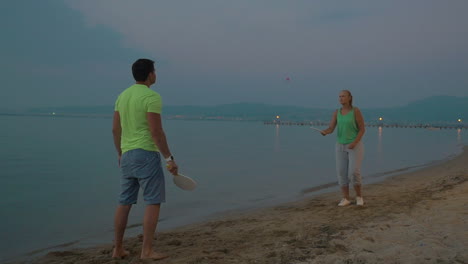 hombre y mujer jugando al bádminton en la costa