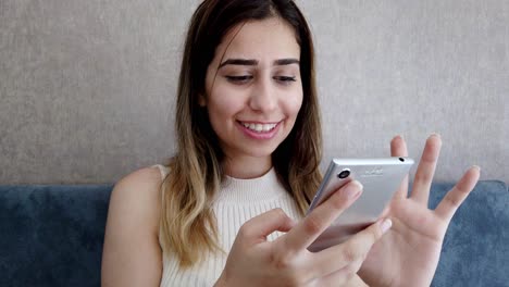 una joven hermosa usa un teléfono inteligente en una silla en una cafetería o restaurante