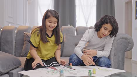 una niña india feliz termina su dibujo y se lo muestra a su hermano