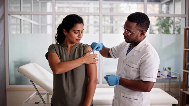 Preparing clinician in coat and blue gloves cleaning patient arm at clinic giving shot with needle