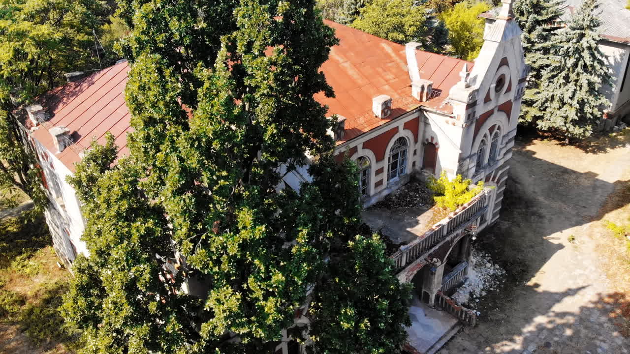 The Pommer Mansion, old abandoned building with green trees and benches on the yard. Aerial drone view. Țaul, Moldova