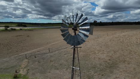 aerial drone orbiting around old windmill with spinning blades at farm, margaret river region in western australia