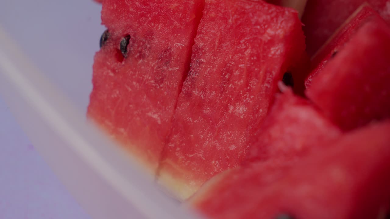 Use a fork to remove a piece of watermelon from a bowl