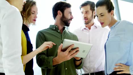 Smiling-business-team-discussing-over-digital-tablet