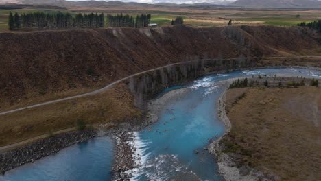 stunning blue glacier river with group of kayakers within expansive, mountainous landscape