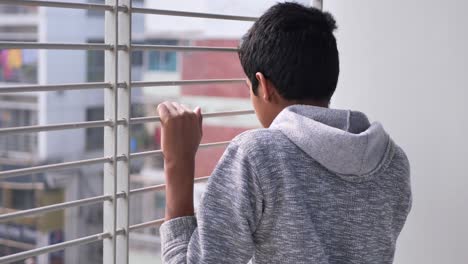 sad teenage boy looking through window