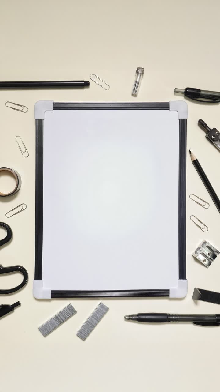 Portrait stop motion of black stationery framing a whiteboard on light background with copy space