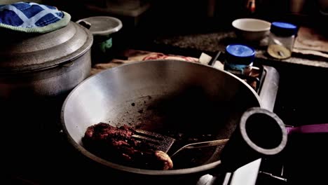 frying a chicken leg in vegetable oil over a gas range in a typical filipino home